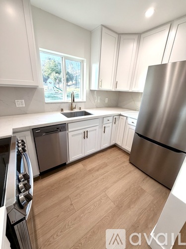 A kitchen with a stainless steel refrigerator and wooden flooring.