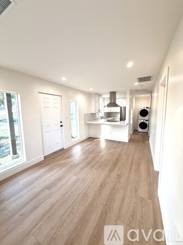 A spacious room with wooden flooring and white walls.