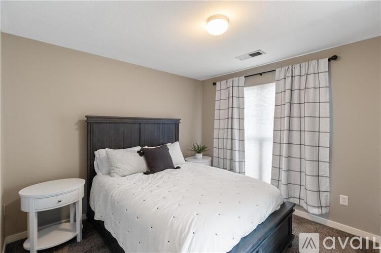 A bedroom with a bed, nightstand, and window.