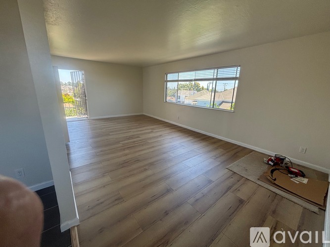 A room with wooden flooring and a window with blinds.