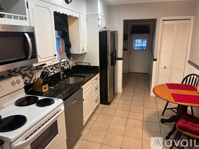 A kitchen with white cabinets and black countertops.
