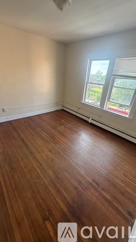 A room with wooden floors and a window showing a view of a garden.