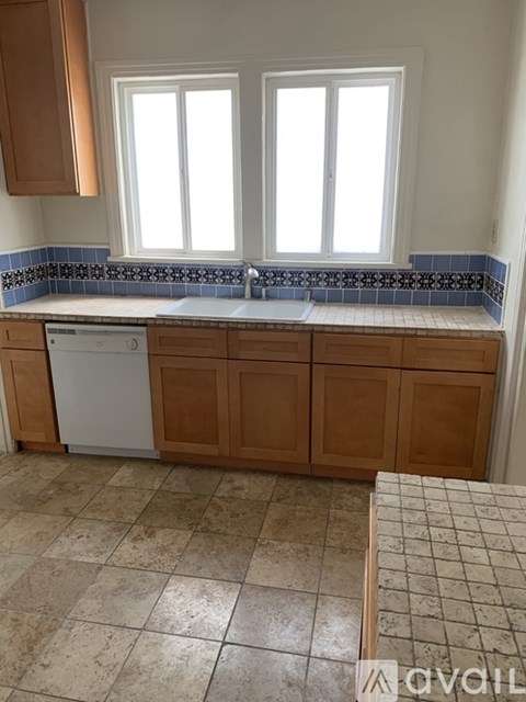 A kitchen with brown cabinets and a white dishwasher.