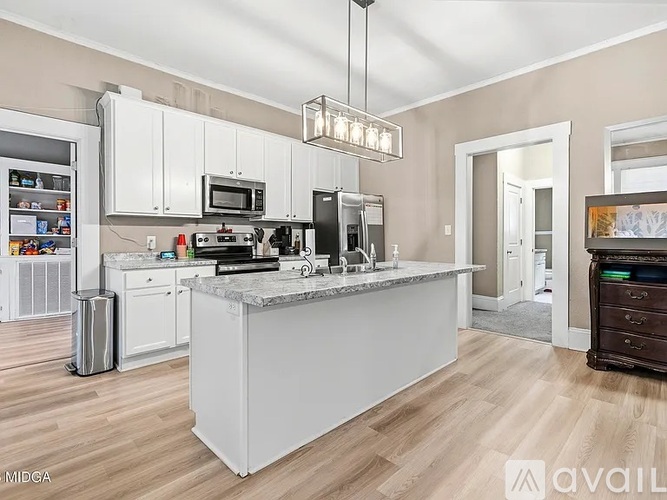 A kitchen with a white island and wooden floors.