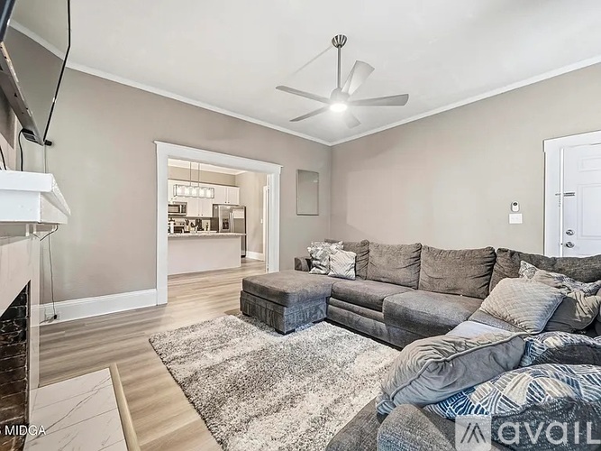 A living room with a grey couch and a white ceiling fan.