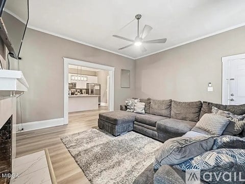 A living room with a grey couch and a white ceiling fan.