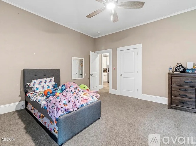 A bedroom with a bed, dresser, and ceiling fan.