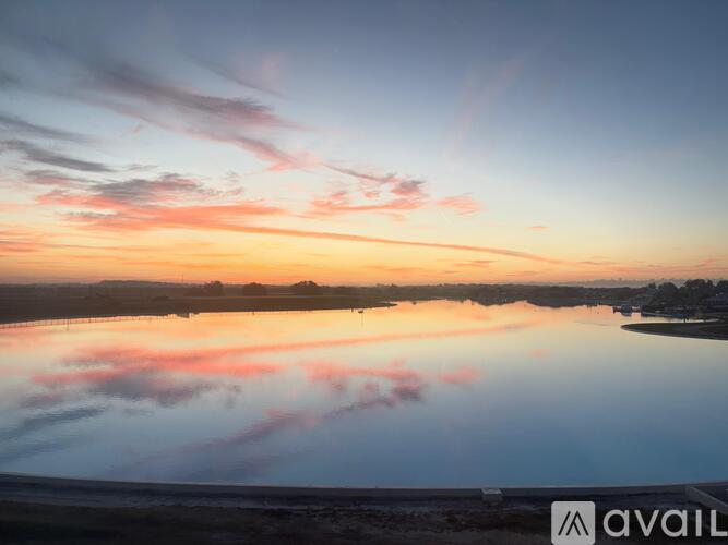 A serene landscape with a body of water reflecting the sky at sunrise or sunset.