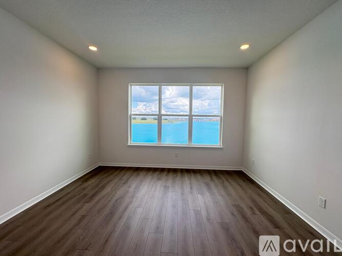 A room with wooden floors and a large window overlooking the beach.