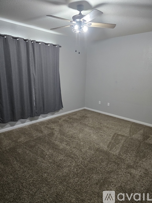 A room with a ceiling fan and carpeted floor.