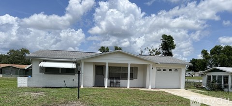 A white house with a grey roof and a garage door.