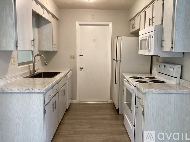A kitchen with white cabinets and appliances is available for rent.