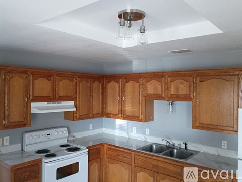 A kitchen with wooden cabinets and a white stove top oven.