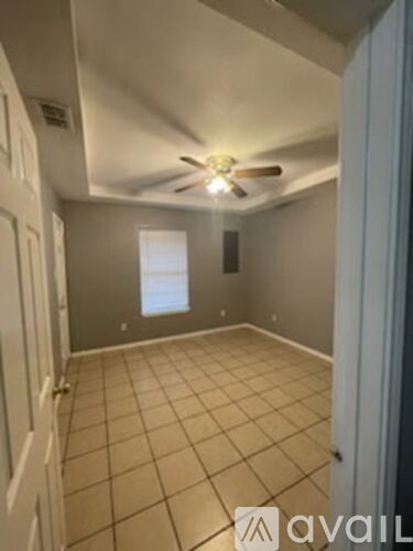 A room with a ceiling fan and tile flooring.