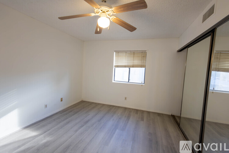 A room with a ceiling fan and a window with blinds.