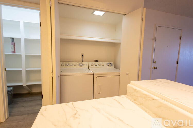 A bedroom with a bed, a washing machine, and a dryer in the laundry area.