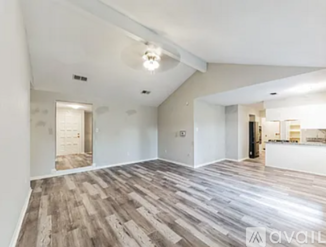 A spacious room with wooden flooring and white walls.