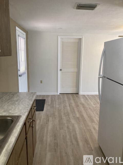 A kitchen with a white refrigerator, sink, and wooden cabinets.