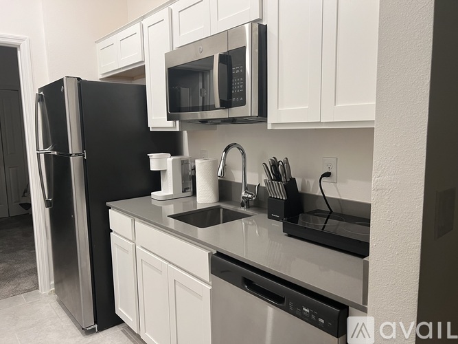 A kitchen with a black fridge and white cabinets.
