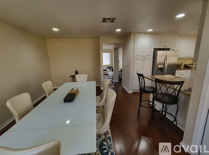 A dining room with a white table and chairs.