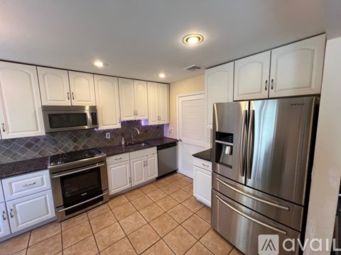 A kitchen with white cabinets and a stainless steel refrigerator.