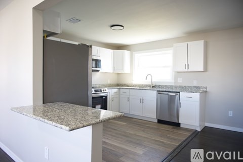 A kitchen with white cabinets and a granite countertop.