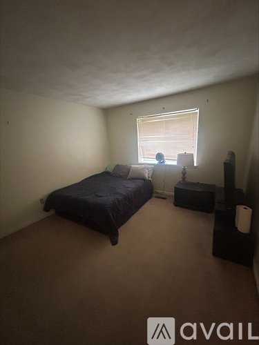 A bedroom with a bed, nightstand, and window.