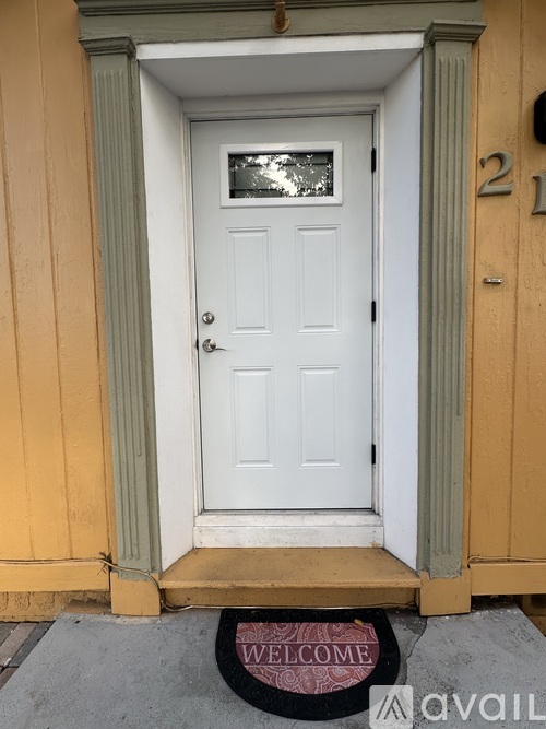 A white door with a glass window and a welcome mat in front.