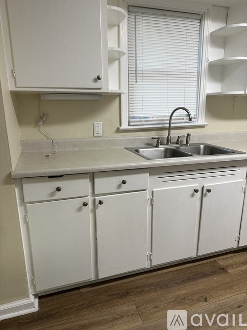 A kitchen with white cabinets and a stainless steel sink.