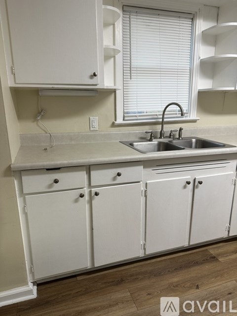 A kitchen with white cabinets and a stainless steel sink.
