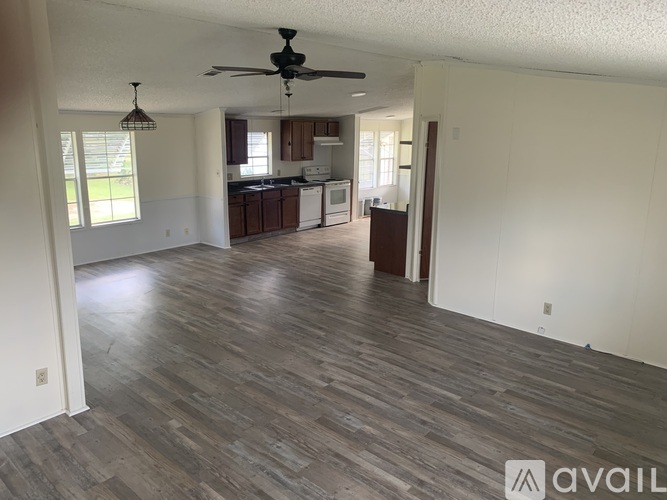 A spacious living room with a kitchen in the background.