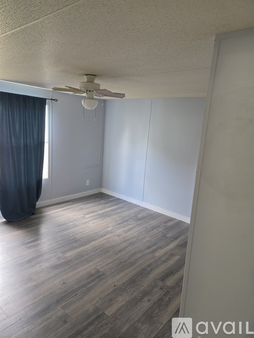A room with a ceiling fan and wooden flooring.