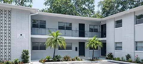 A white building with a balcony and a black door.