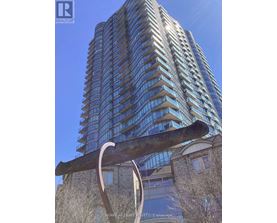 A tall building with many windows and a sculpture in front of it.