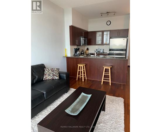 A black couch sits in a living room with a wooden coffee table in front of it.