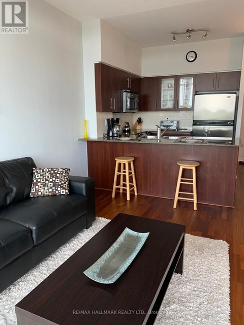 A black couch sits in a living room with a wooden coffee table in front of it.
