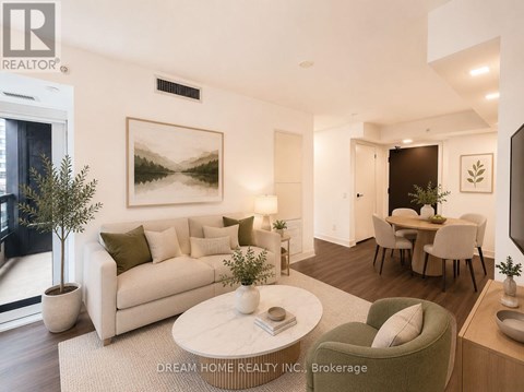 A modern living room with a large painting on the wall and a dining area in the background.