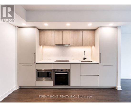 A modern kitchen with a sink, stove, and cabinets.