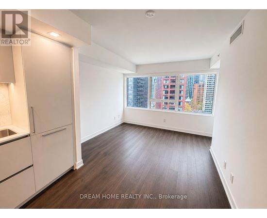 A room with wooden floors and white walls, with a window showing a city view.