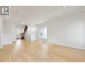 A spacious room with wooden flooring and white walls.