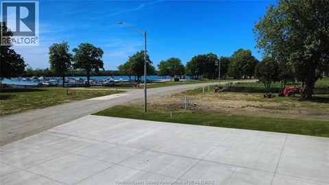A realtor image of a driveway leading to a grassy area with trees.