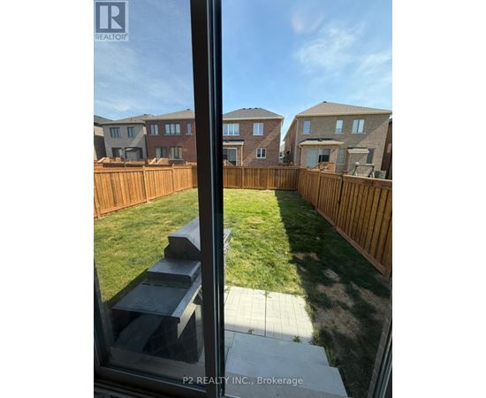 A view from a window looking out at a backyard with a wooden fence and houses in the background.
