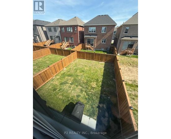 A backyard with a wooden fence and a grassy area.