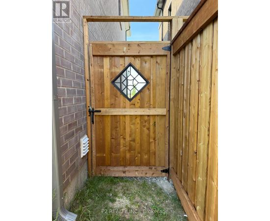 A wooden gate with a diamond-shaped glass window is closed.