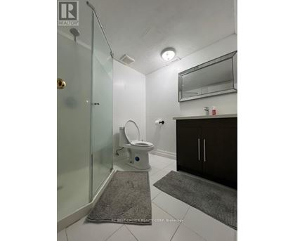 A small white toilet is in a white bathroom with a glass shower door.