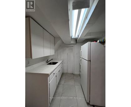 A kitchen with white cabinets and a white fridge.