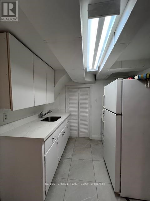A kitchen with white cabinets and a white fridge.