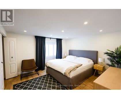 A bedroom with a large bed, a chair, and a plant.