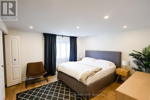 A bedroom with a large bed, a chair, and a plant.
