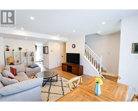 A living room with a couch, a coffee table, and a staircase.